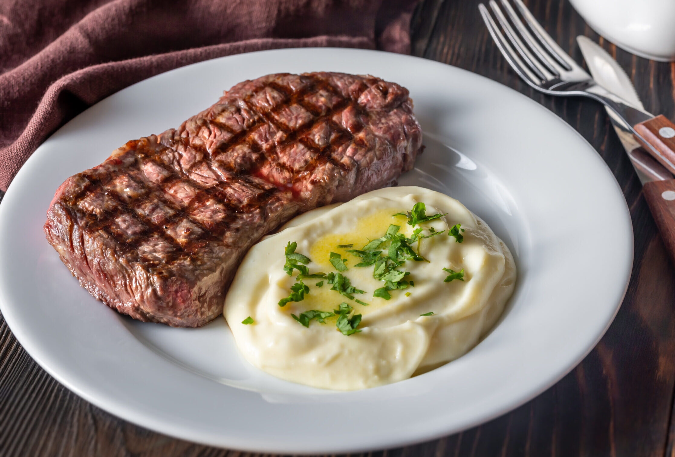 Steak and mashed potatoes on a plate.