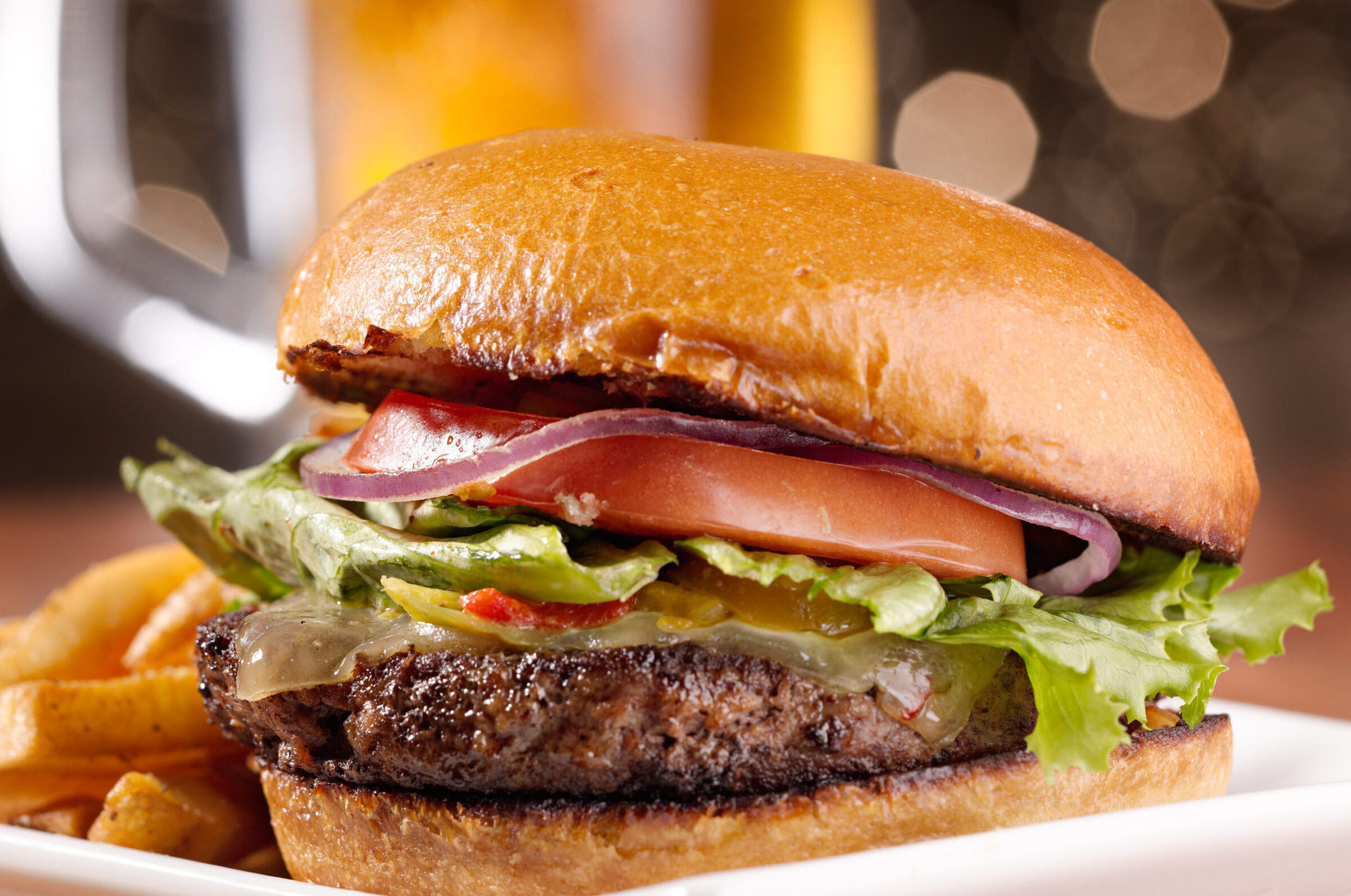 hamburger with toppings and fries on a plate.