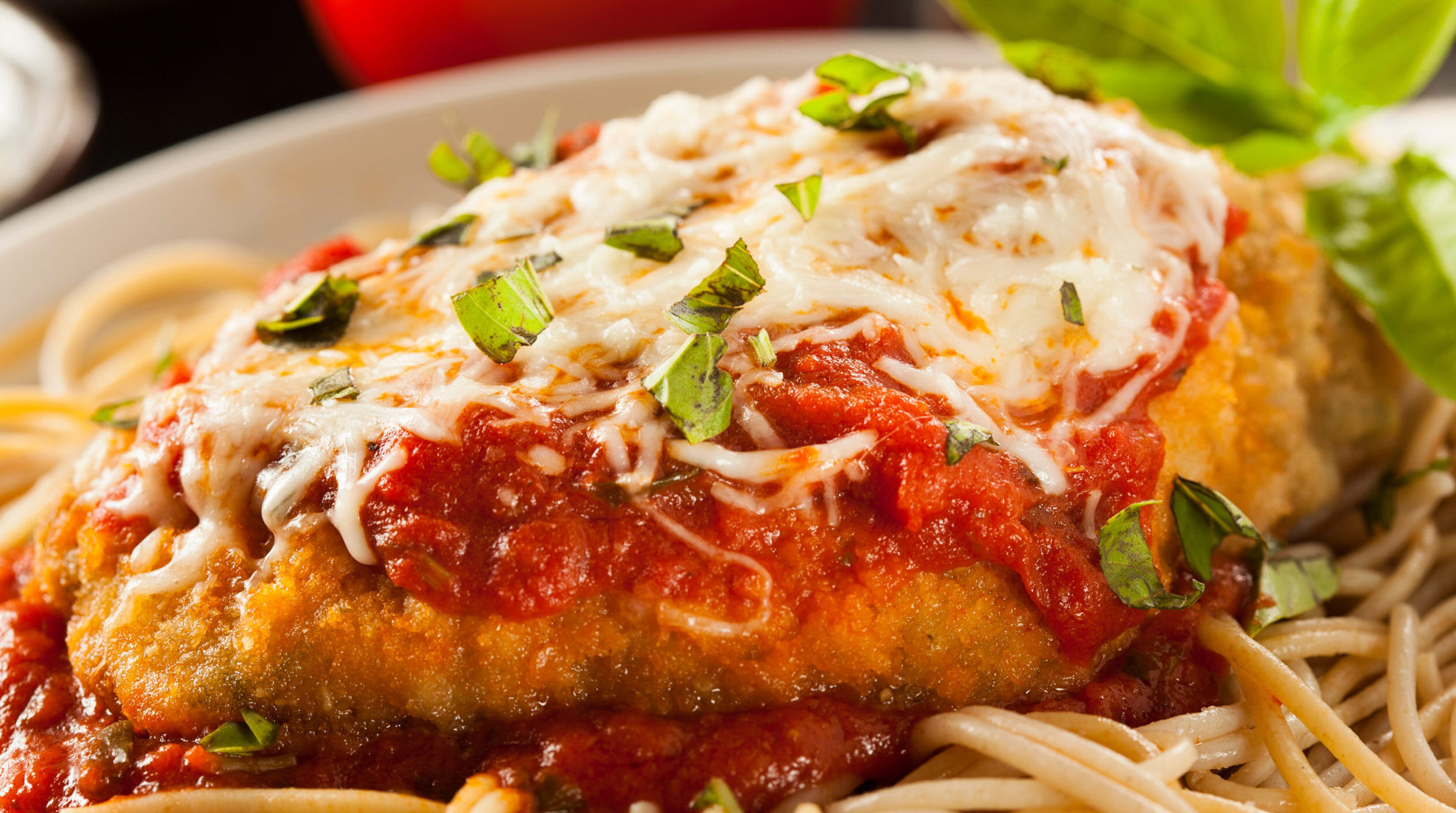 Chicken parmesan sitting on pasta noodles