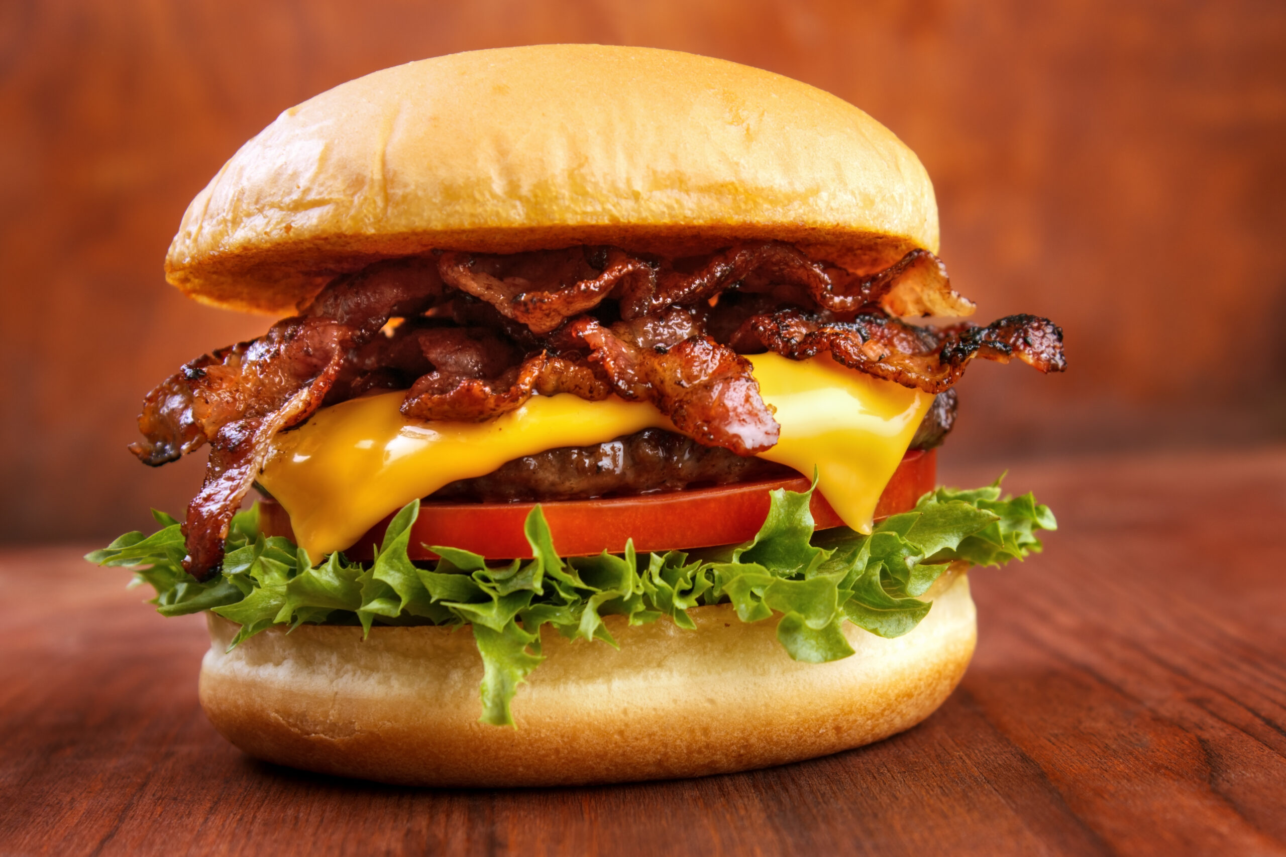 Bacon cheeseburger with lettuce and tomatoes.